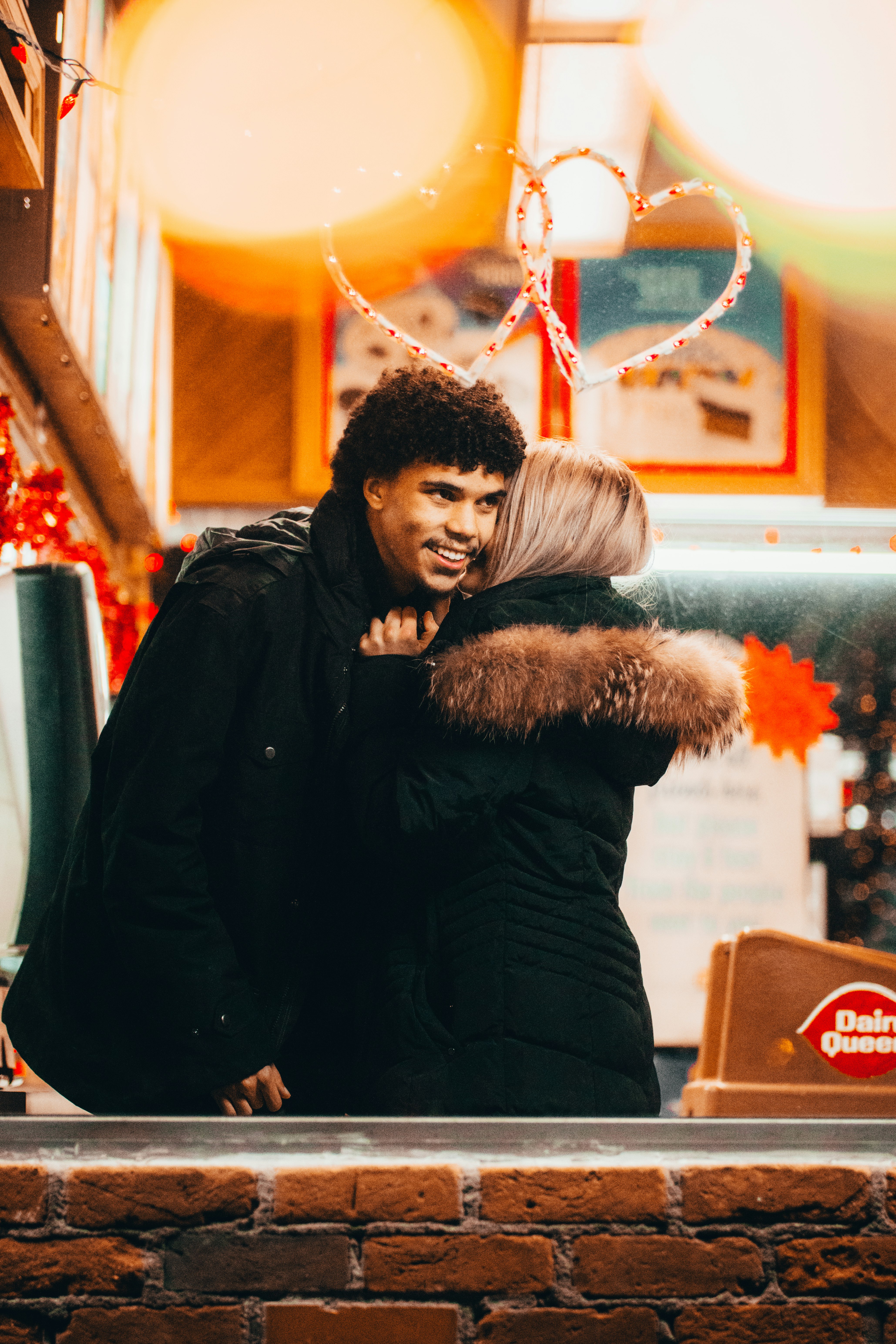 man in black jacket hugging woman in black fur coat